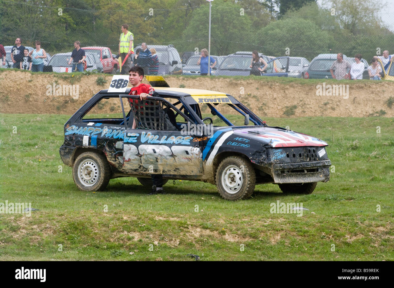 Driver getting out of Banger Racing Car Smallfield Raceway Surrey Damaged Dented Cars Stock Photo