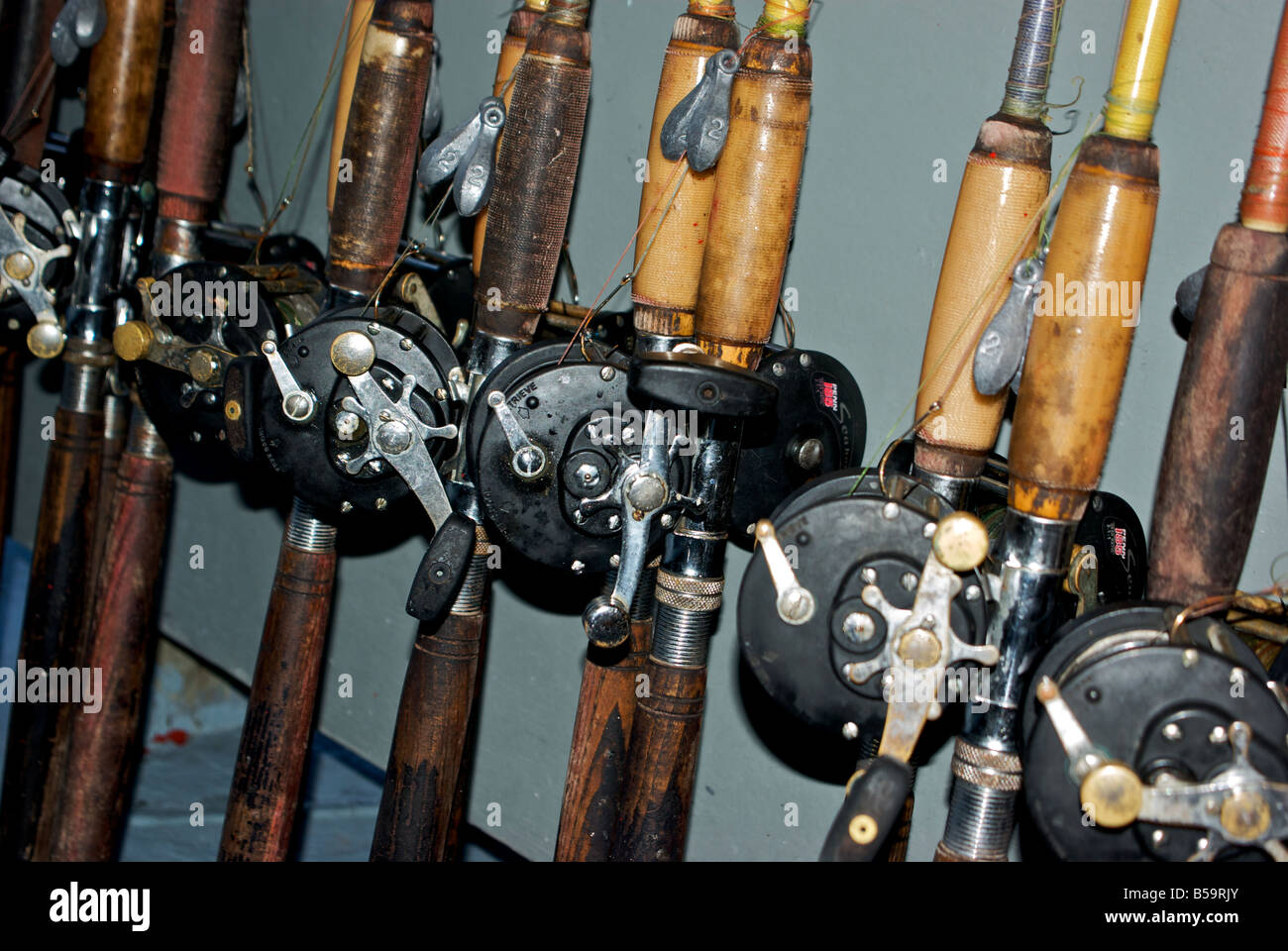 Well used fishing rods and reels ready to use on a party fishing boat rack  Stock Photo - Alamy