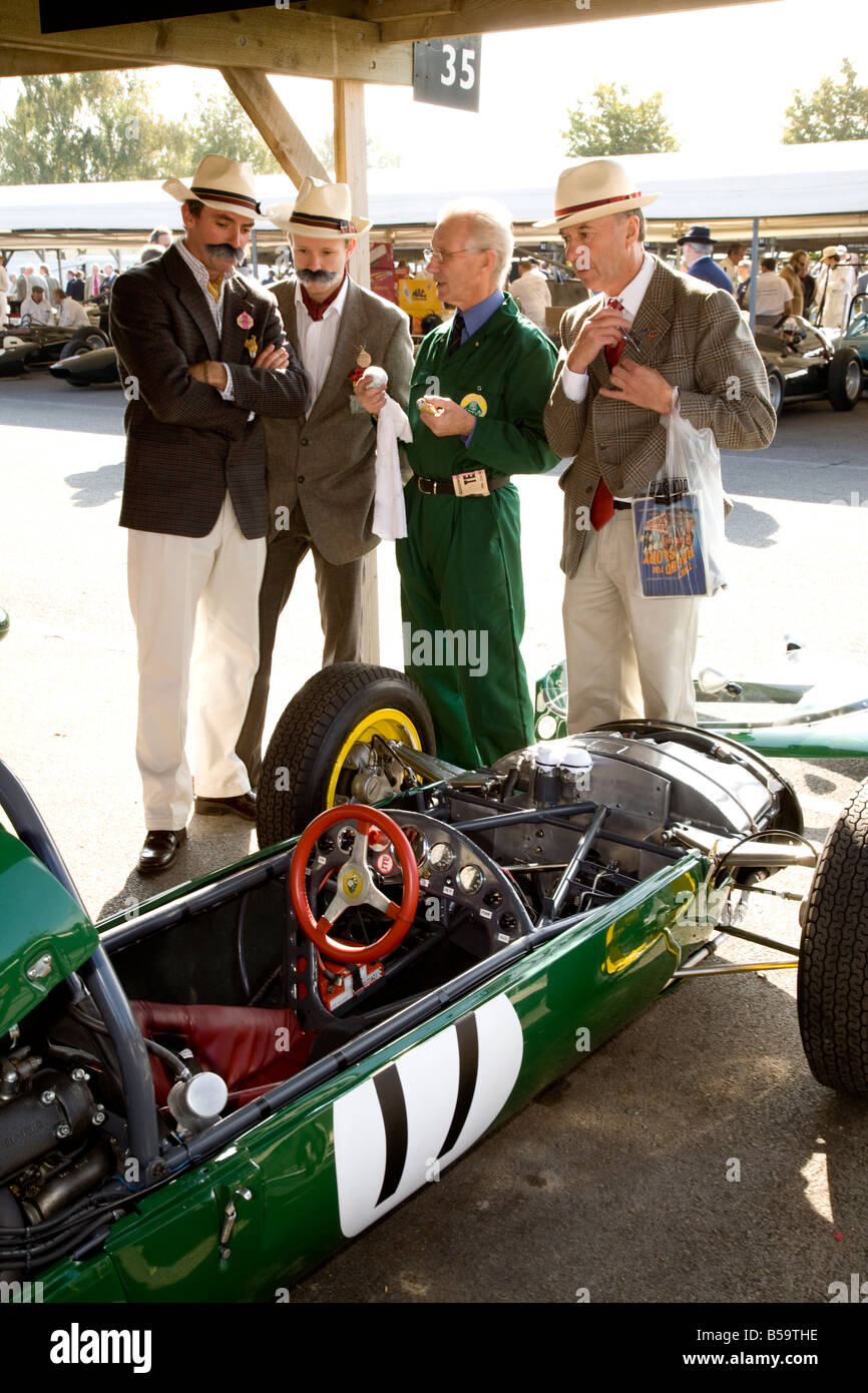 In appropriate dress, 4 visitors to the Goodwood Revival meeting, talk about the Lotus-Climax in the paddock. Stock Photo