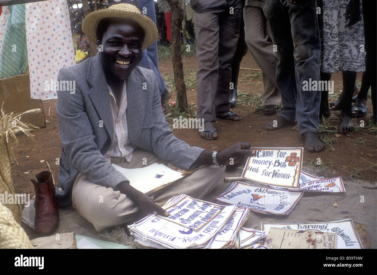 Black African man market trader selling offering for sale mottoes and local sayings at rural market in Uganda Stock Photo