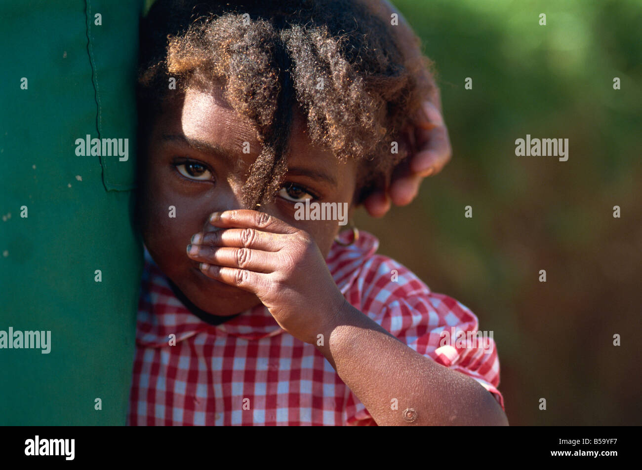 Small child in red check shirt at mother's side, Godet, Haiti, West Indies, Central America Stock Photo