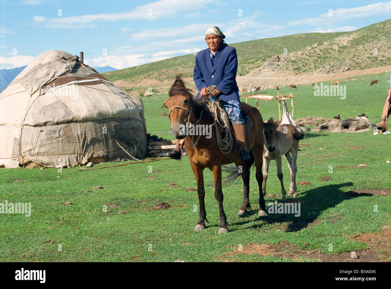 Kazak woman on horseback beside a yurt in the Altay mountains north ...