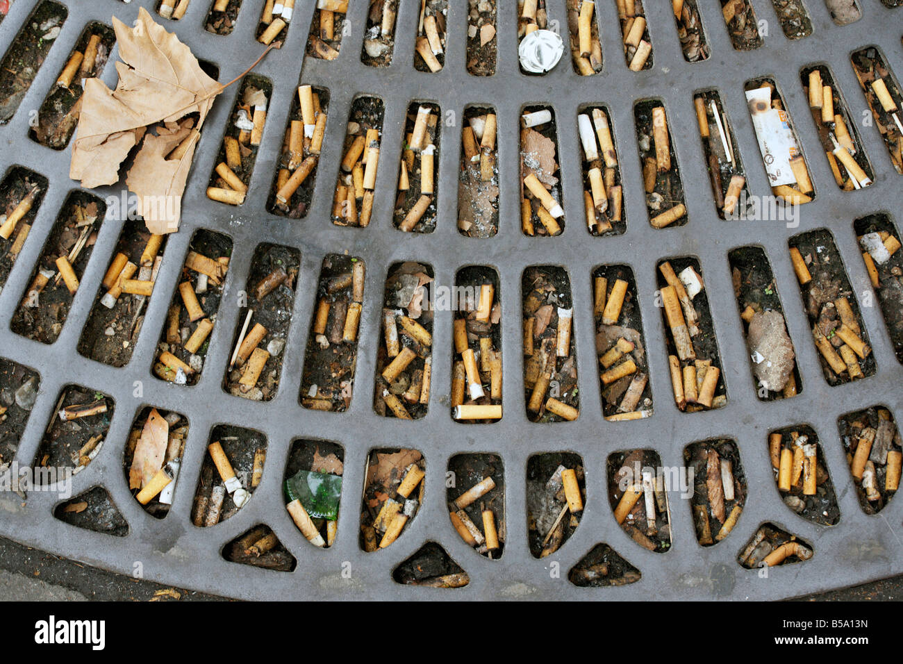 Discarded cigarette butts on a pavement in Paris Stock Photo