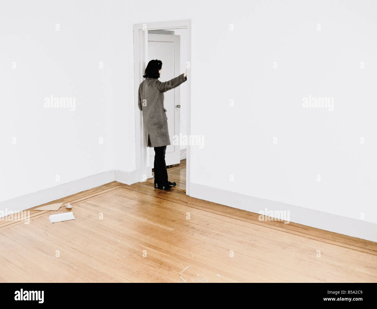 Woman Leaning Against Doorframe In Empty Apartment Stock Photo