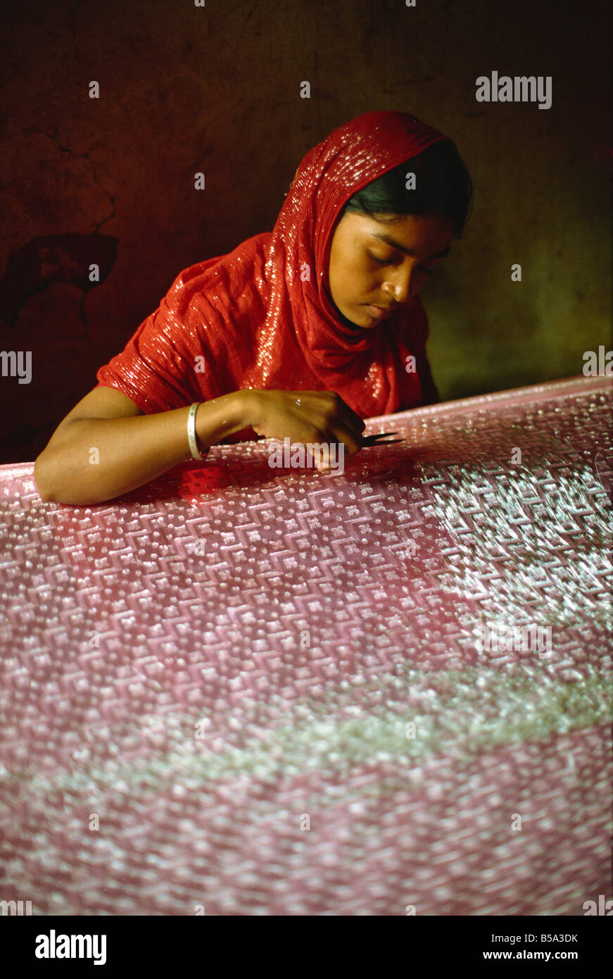 Clipping and finishing off a Benares silk sari Varanasi Uttar Pradesh state India Asia Stock Photo