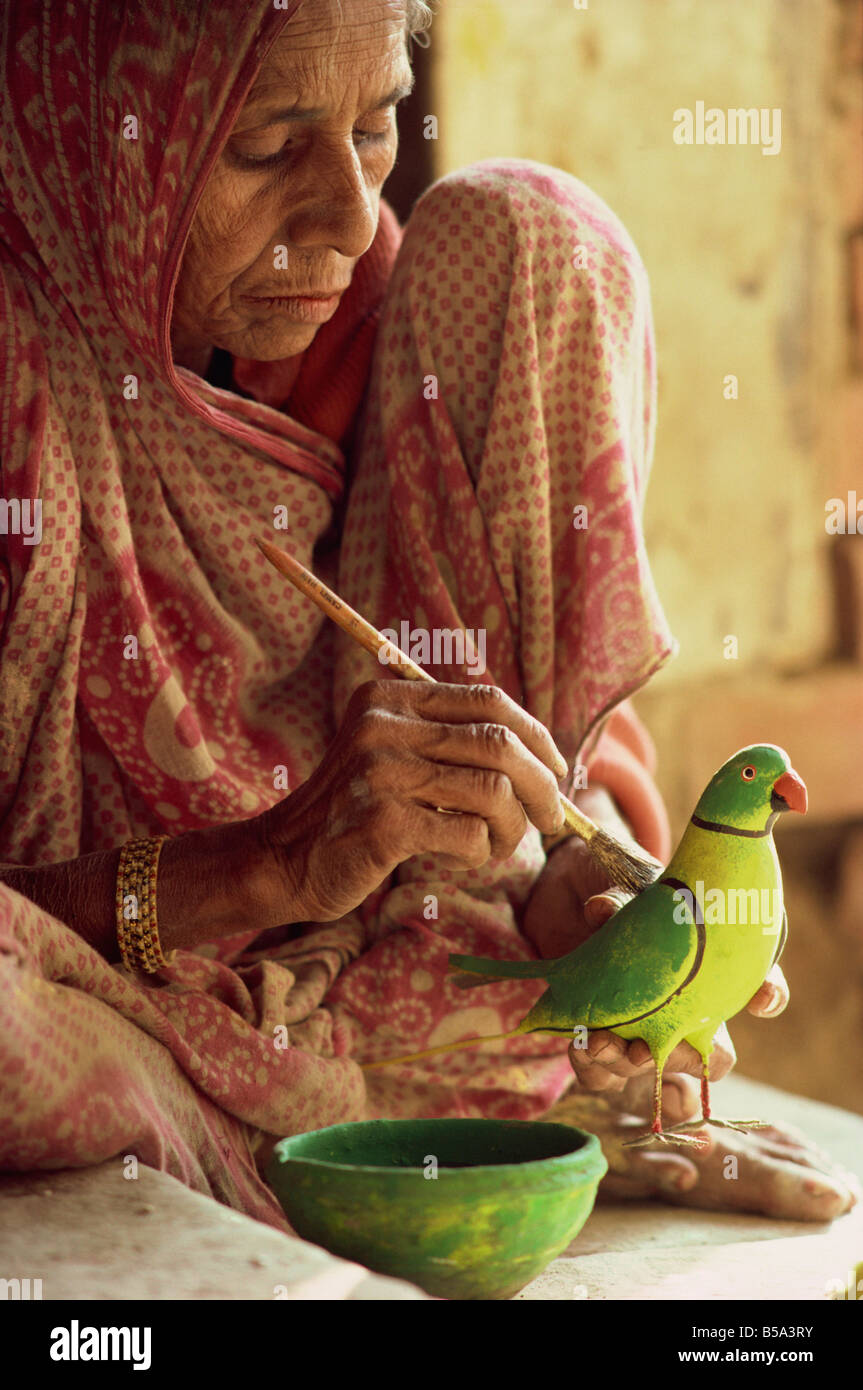 A woman paints a clay toy parrot northern India India Asia Stock Photo