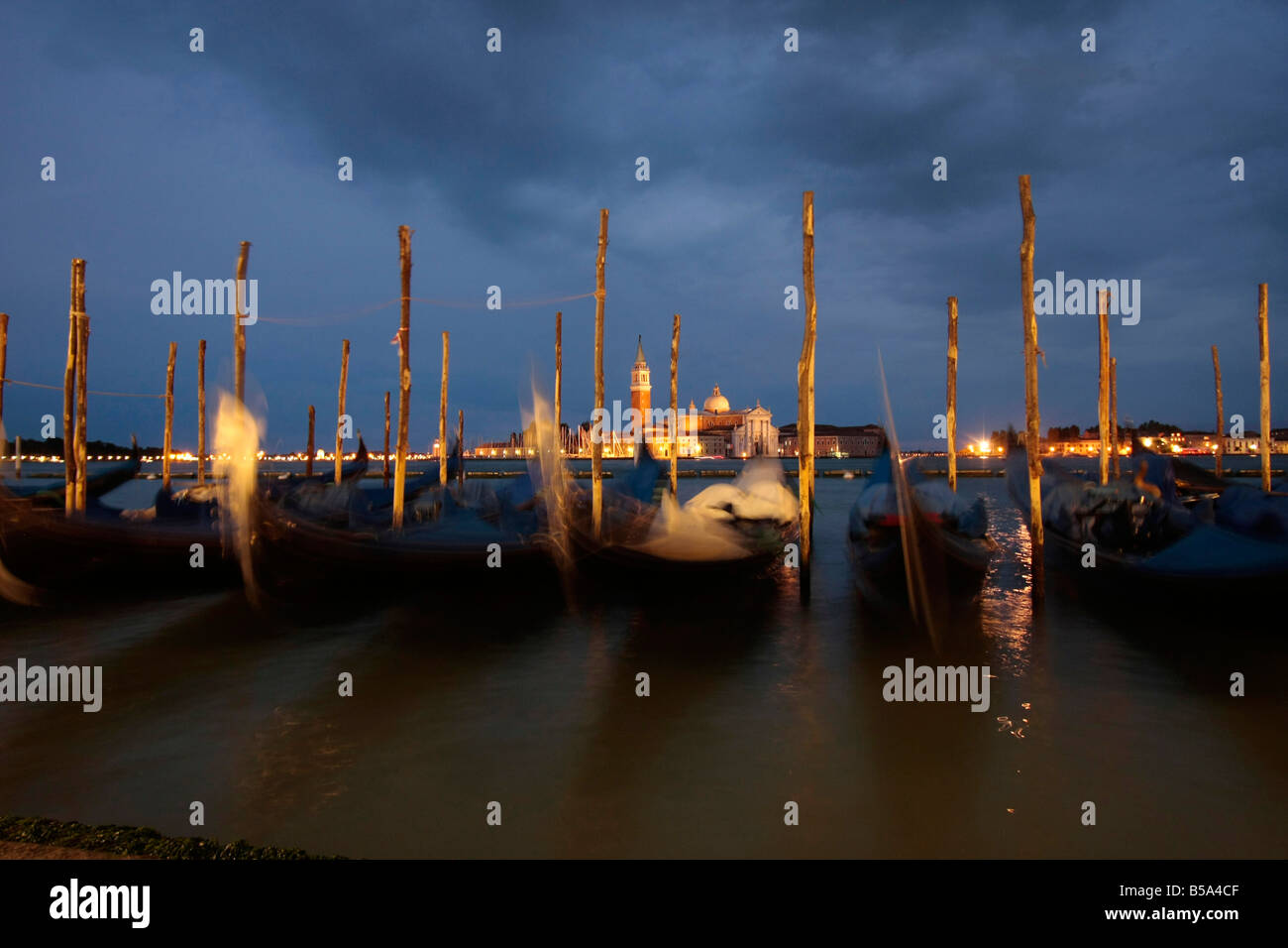 gondolas at the waterfront facing the lagoon and San Giorgio Maggiore Island at night in Venice Italy Stock Photo