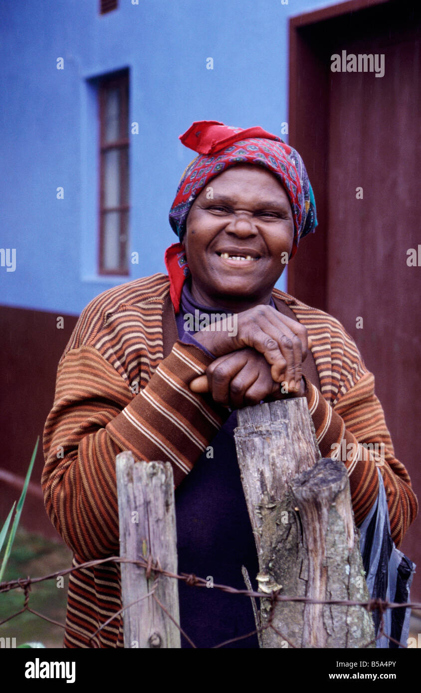 Mature woman smiling Missing top teeth Blue house wall WOMAN SWAZILAND Stock Photo