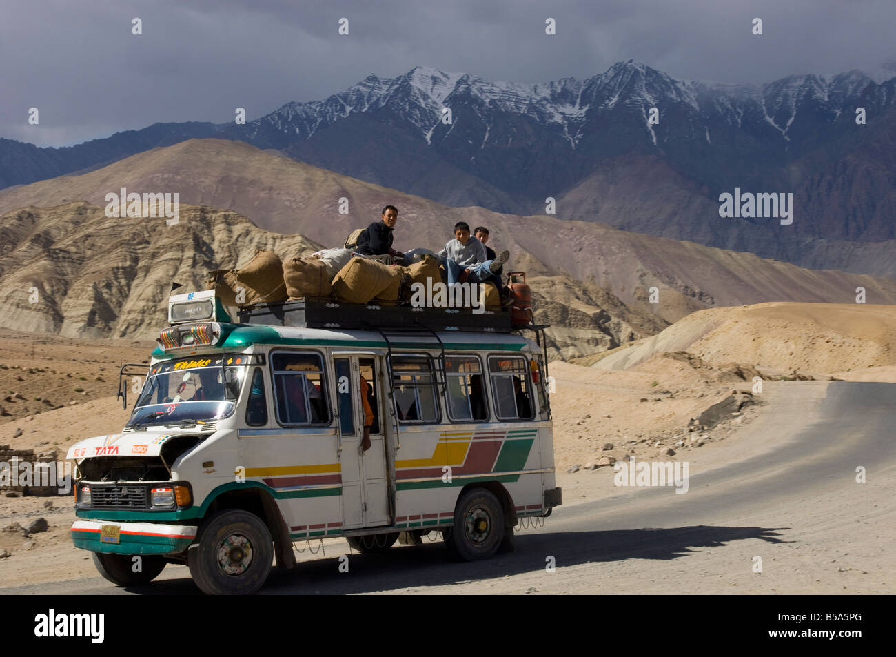 Loaded mini bus with half open engine lid and people sitting on the roof top, Indus Valley, Ladakh, India Stock Photo