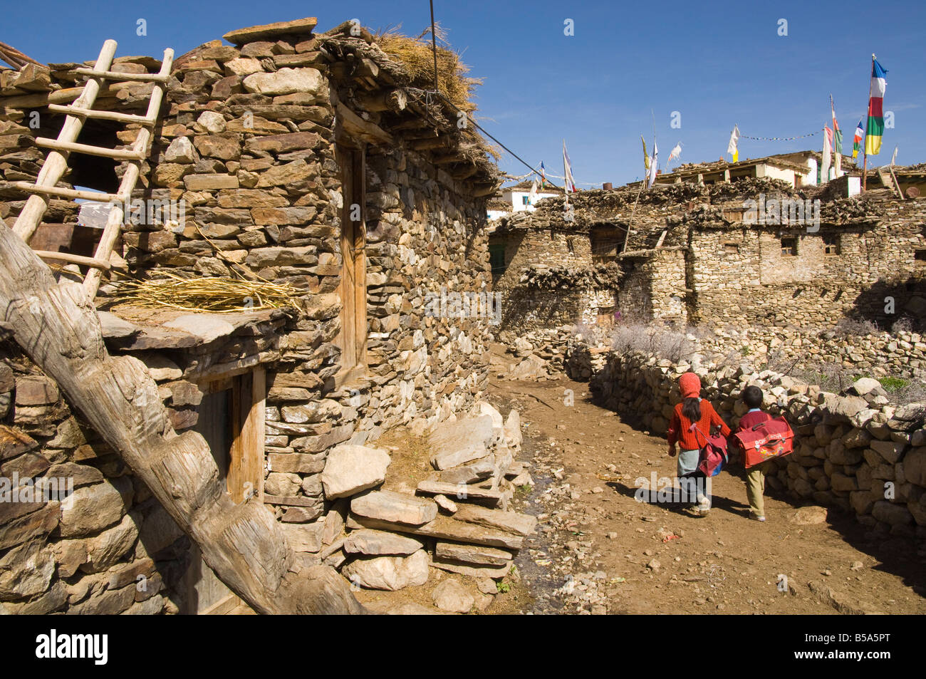 Two schoolchildren and typical stone houses on village street, Nako, 2950 m, Spiti, Himachal Pradesh, India Stock Photo