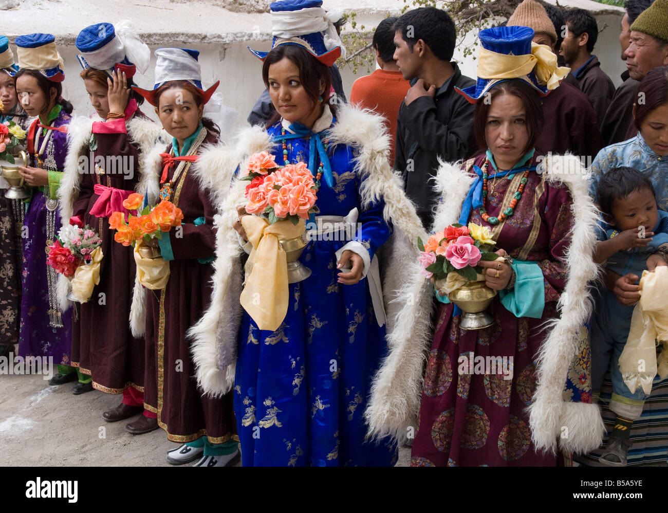 Group of young local women in full traditional costume waiting in a row for Lama, Alchi, Ladakh, India Stock Photo
