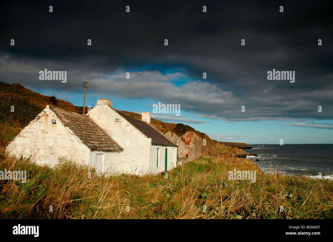 A whitewashed cottage and adjacent stone ruin lie on the N.E coast of scotland. Stock Photo