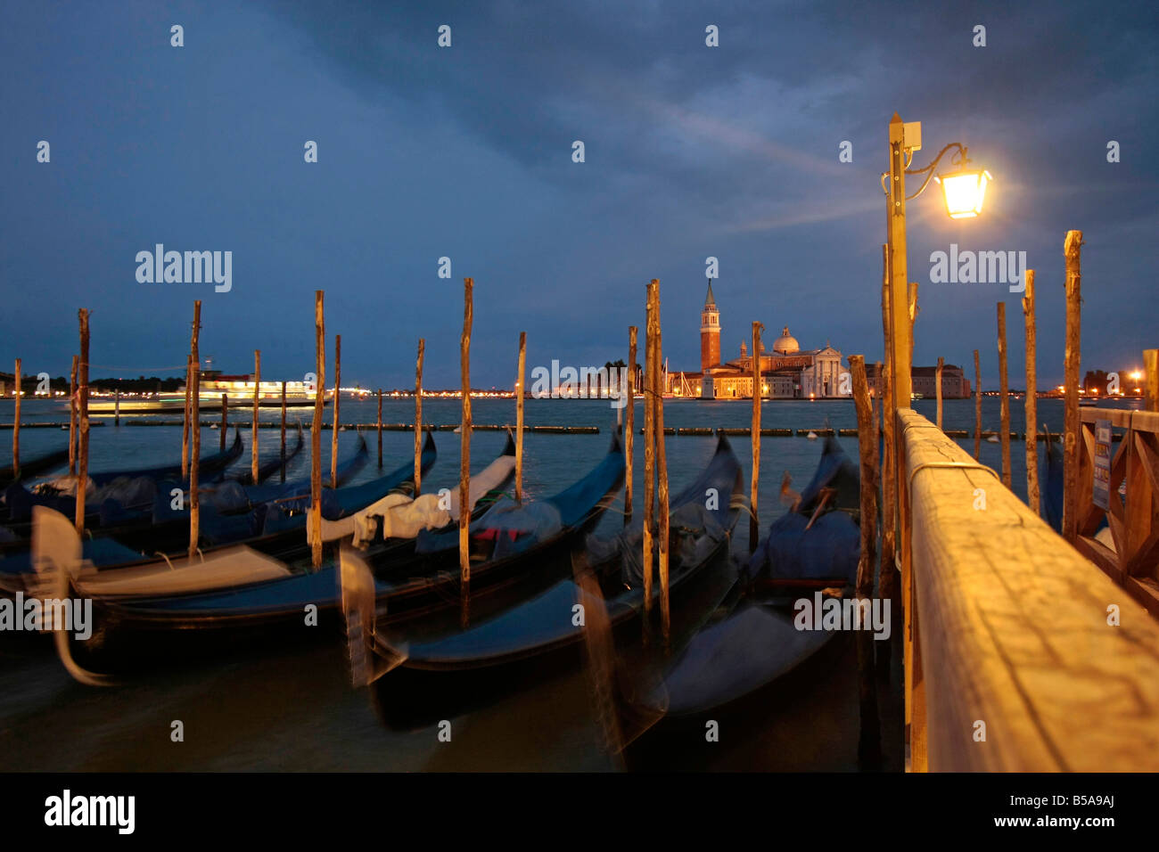 gondolas at the waterfront facing the lagoon and San Giorgio Maggiore Island at night in Venice Italy Stock Photo