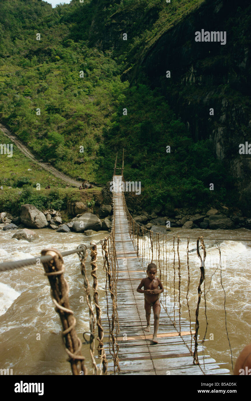 Child crossing bridge South Beliam Valley Irian Jaya Indonesia Southeast Asia Asia Stock Photo