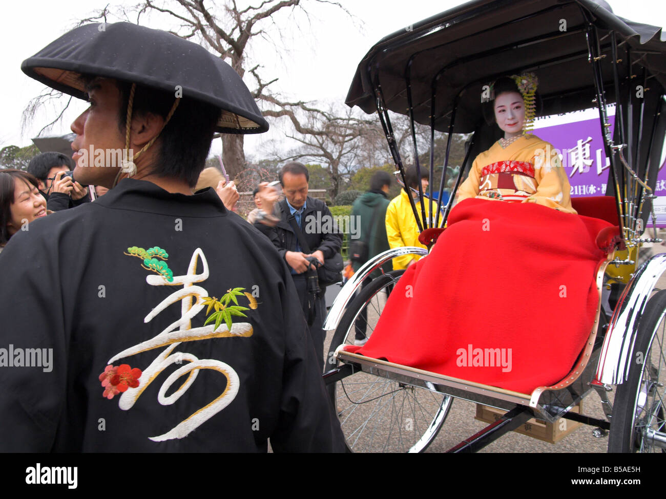 Geisha in full traditional dress and haircut sitting on a rickshaw with red blanket and driver, Kyoto, Kansai, Honshu, Japan Stock Photo
