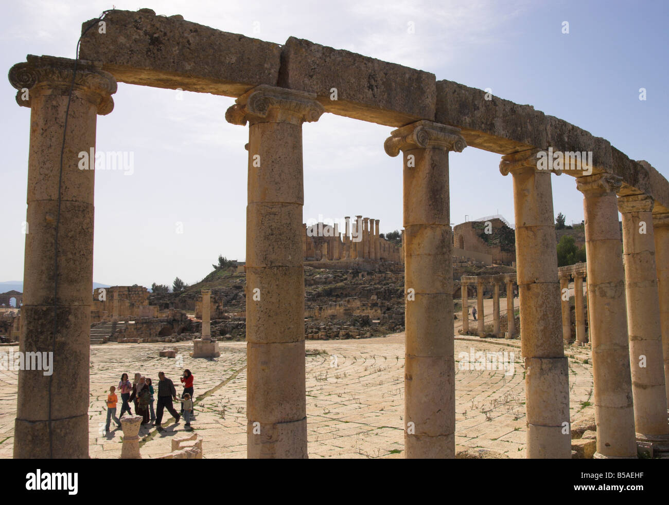Backlit view through columns with family walking past, Jerash, Jordan, Middle East Stock Photo