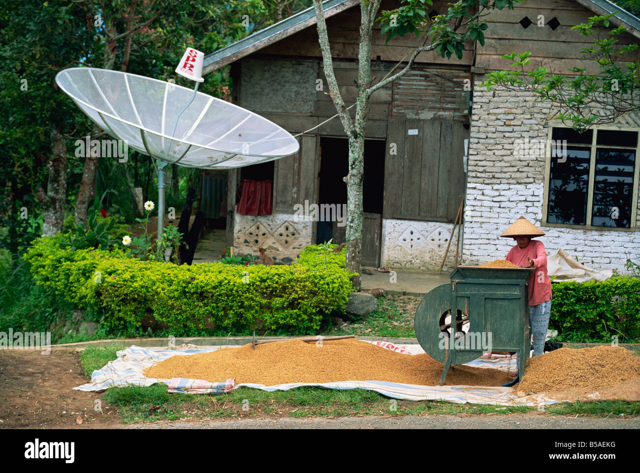 Satellite dish and man with rice winnowing machine, Lake Maninjau, Sumatra, Indonesia, Southeast Asia Stock Photo