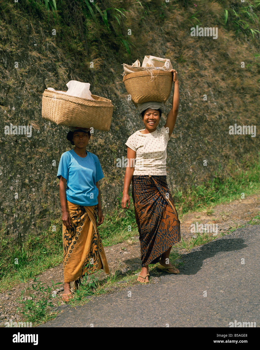 Portrait of two women in traditional dress carrying baskets on their