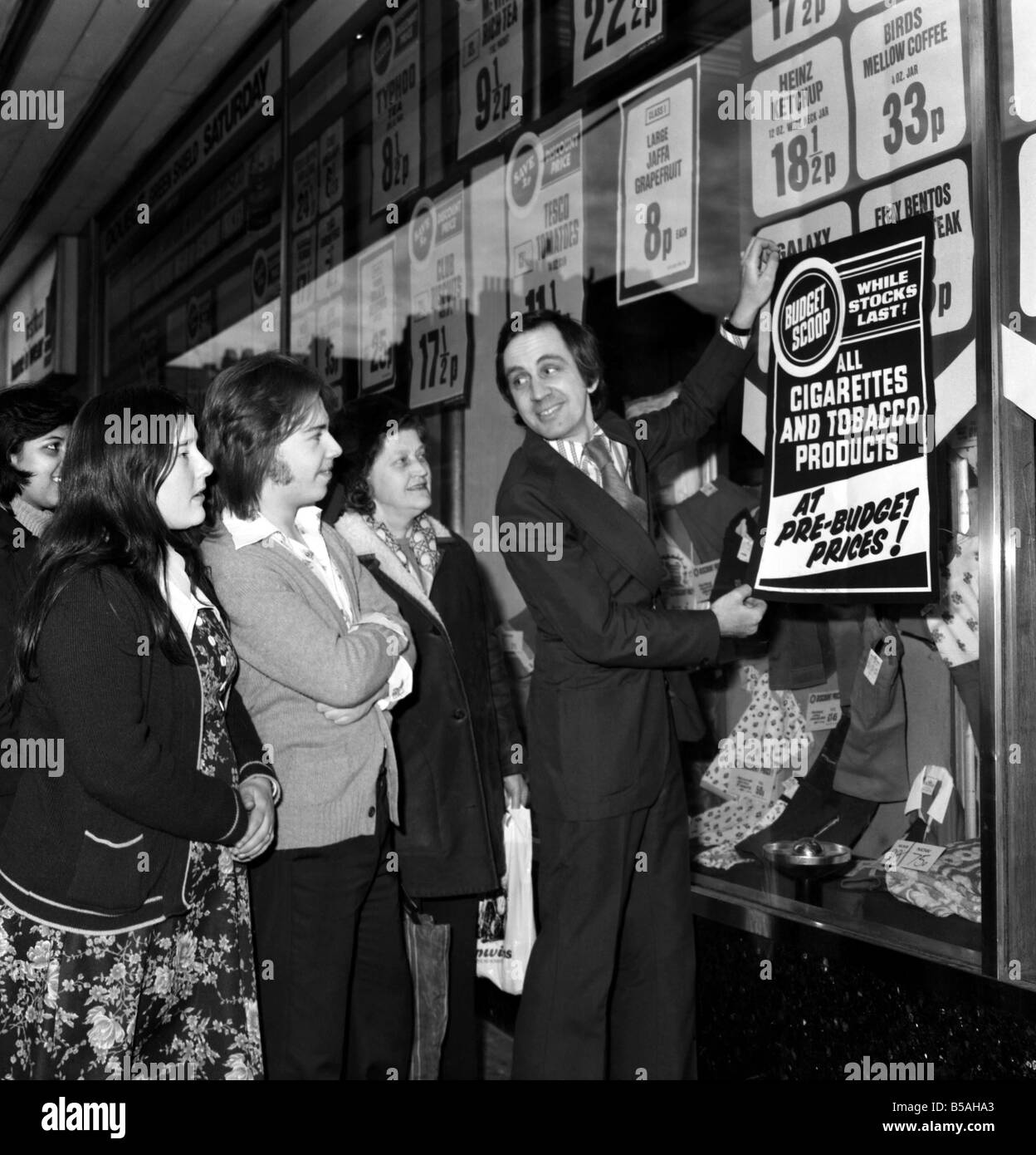 Tesco supervisor Tony Dobbin puts up 'pre-budget prices' posters on one of the company's stores in Camden High Street, London N.W.1. April 1975 Stock Photo