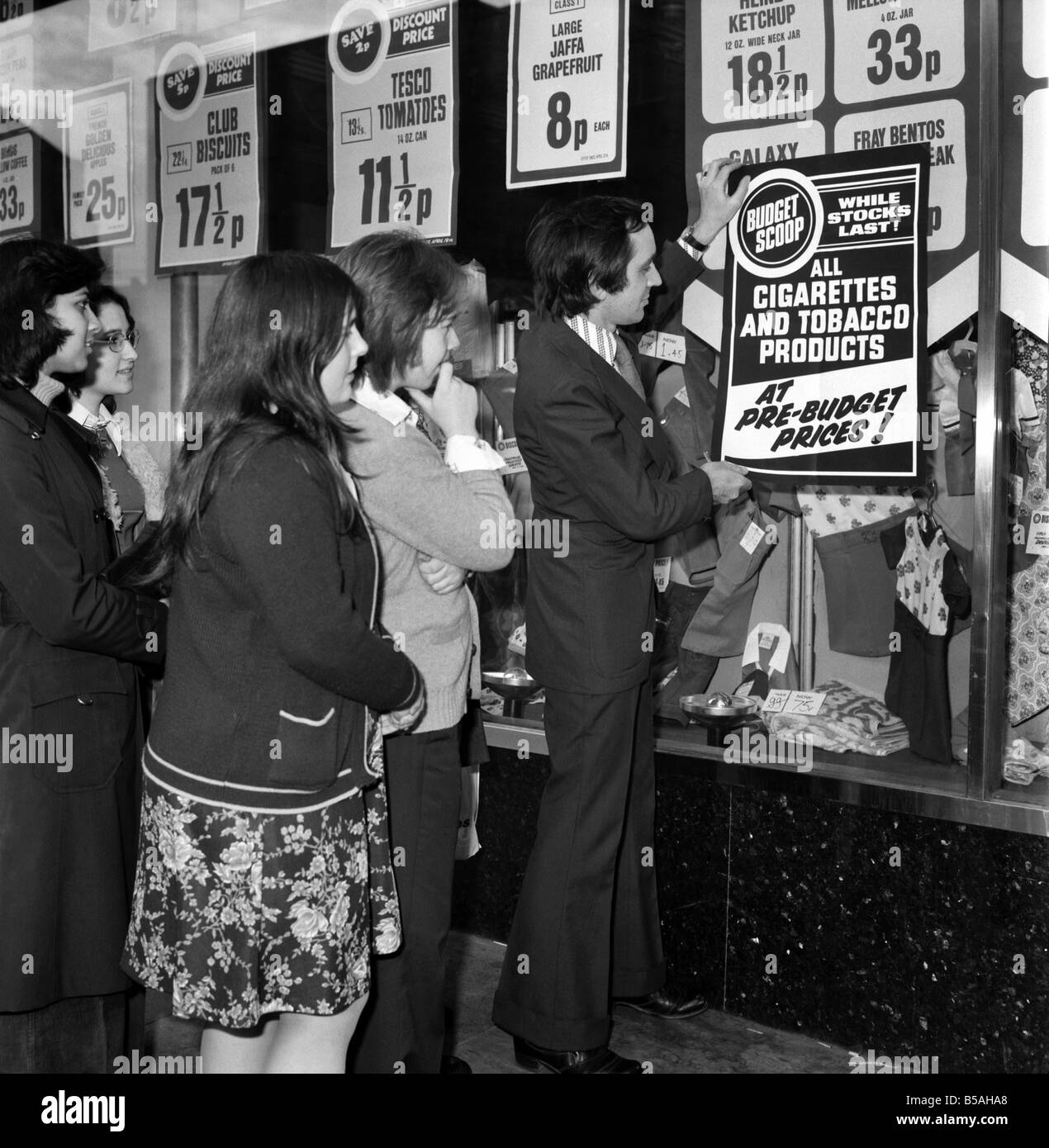 Tesco supervisor Tony Dobbin puts up 'pre-budget prices' posters on one of the company's stores in Camden High Street, London N.W.1. April 1975 Stock Photo