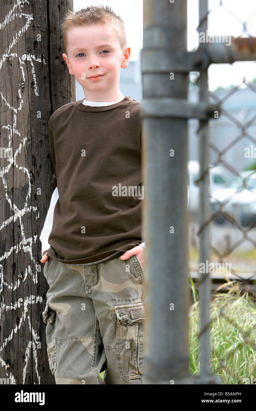 Boy leaning casually against wooden fence Stock Photo