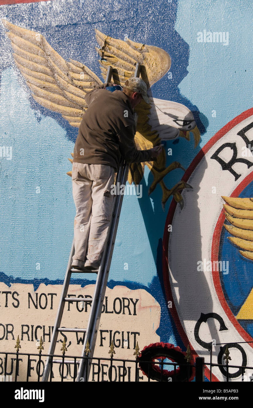 Man on ladder painting a protestant mural off the Shankill Road ...