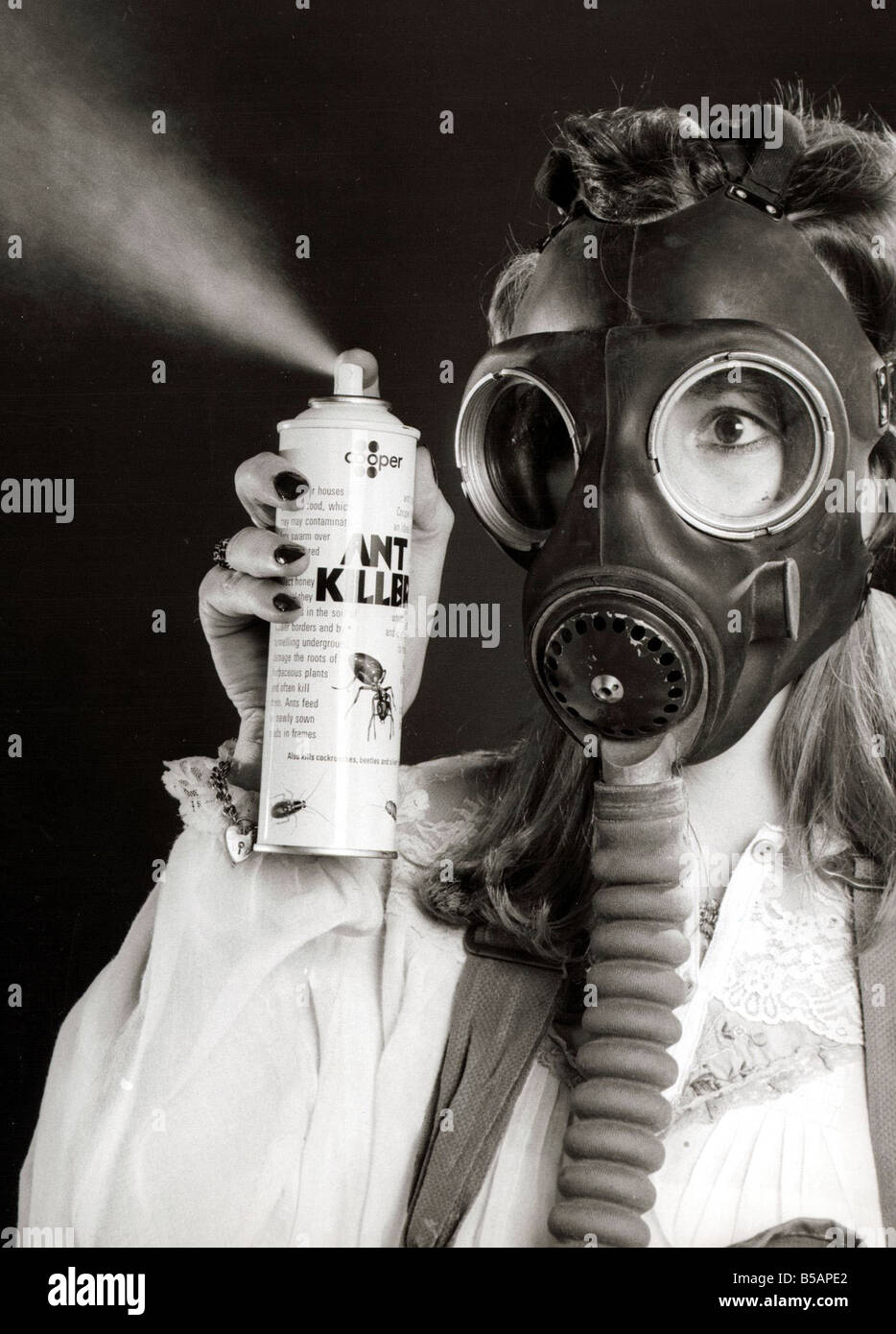 A woman wearing a protective gas mask February 1981 holding and spraying a  can of Ant Killer Spray Pest Control Stock Photo - Alamy