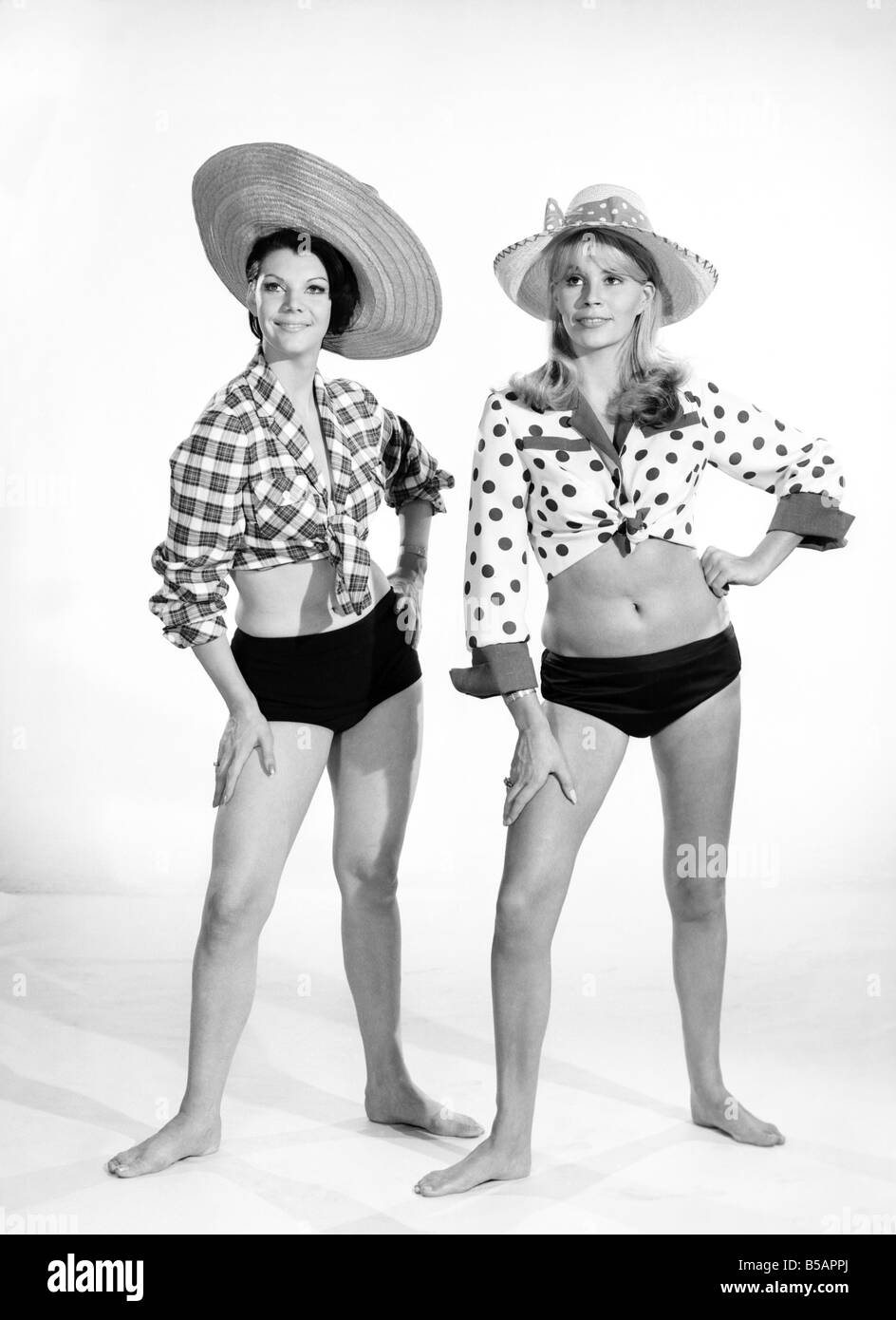 Models Barbara Ray and Jo Ann Asher) seen here modeling swimming costumes and beach coats in the Reveille studios. 1966 Stock Photo