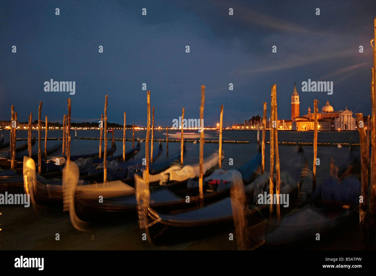 gondolas at the waterfront facing the lagoon and San Giorgio Maggiore Island at night in Venice Italy Stock Photo