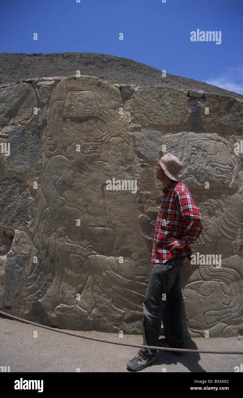 Caucasian tourist face to face with stone warrior dating from approx 2000-1500BC in pre-Chavin site of Cerro Sechín, Casma Valley, Peru Stock Photo