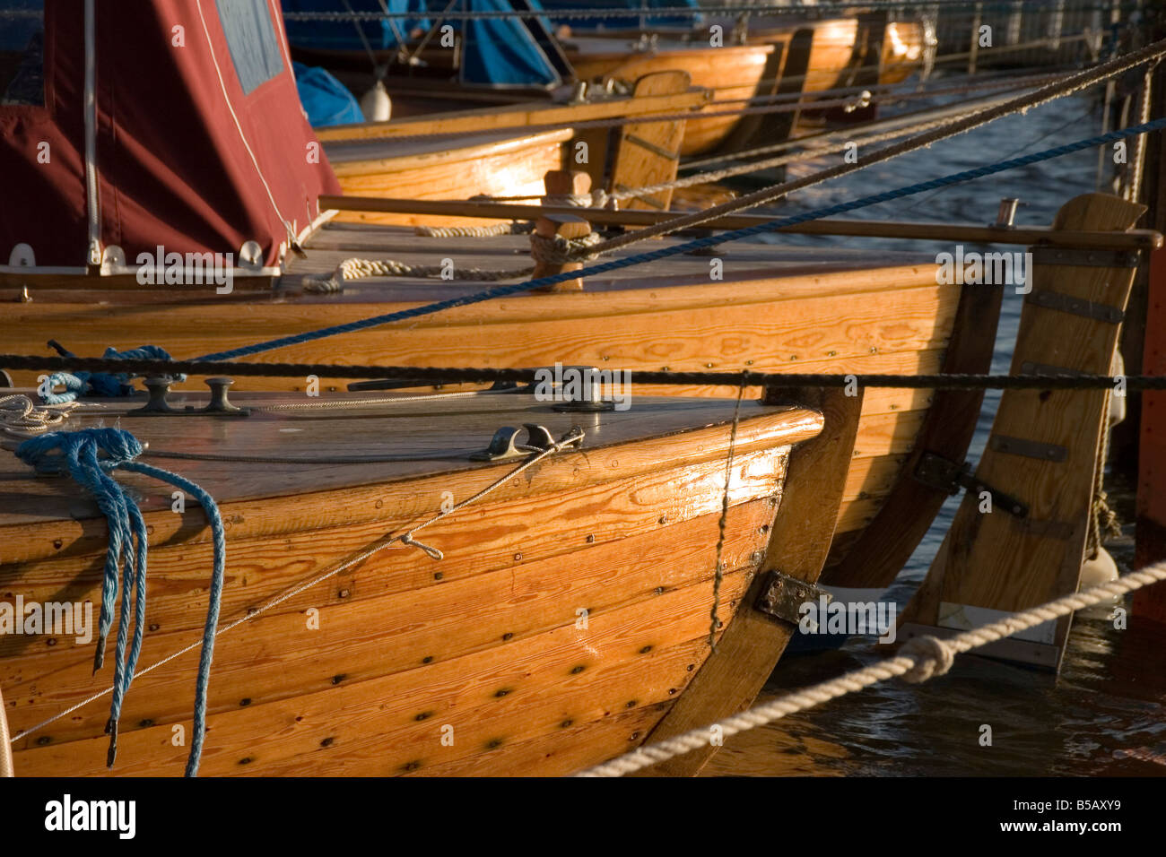 Wooden boats lined up in the summer sun on the river Glomma near the old town of Gamlebyen in Fredrikstad Norway, south of Oslo Stock Photo