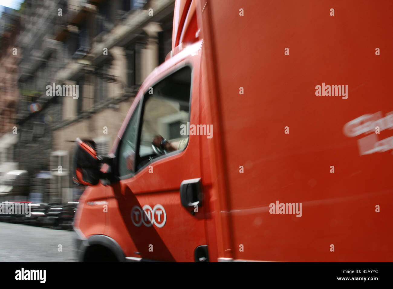fast orange tnt delivery lorry on street in city town Stock Photo