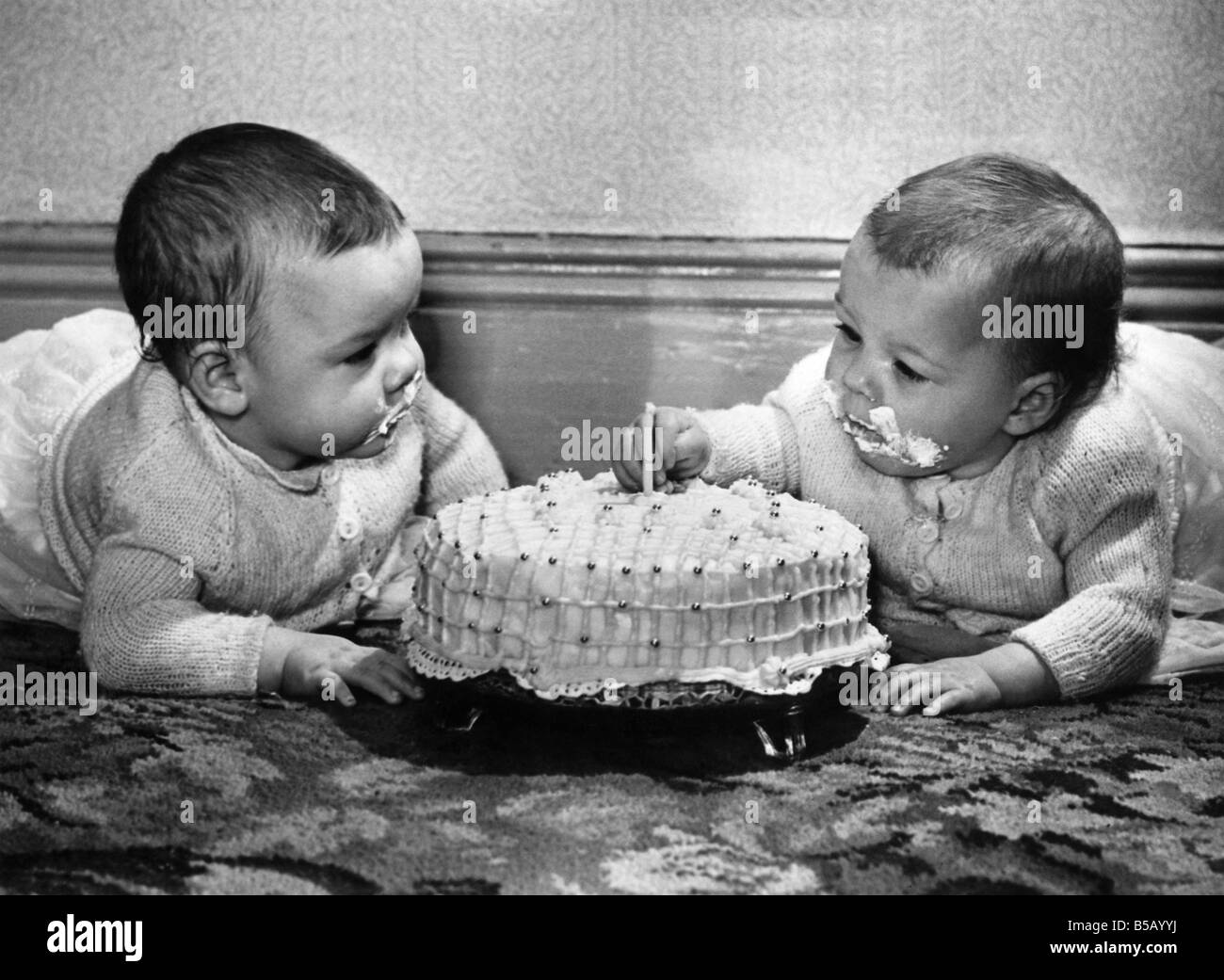LifeÕs a piece of cake now First birthday for two gurgling babiesÑand how they chuckled as they plunged tiny fingers into the icing on the cake baked by Mum. No-one scoldedÑin fact, Mum and Dad just beamed happily. For this was the birthday of the Òbasket twinsÓ Pamela and Suzanne NicholsonÑwho were so small at birth they were not expected to live. But Grannie Emily Keeble told Mum and Dad to keep hopingÑand she was right. Now Pamela is a hefty 15lb. 10oz. and Suzanne is close behind at 14lb. 9oz Stock Photo