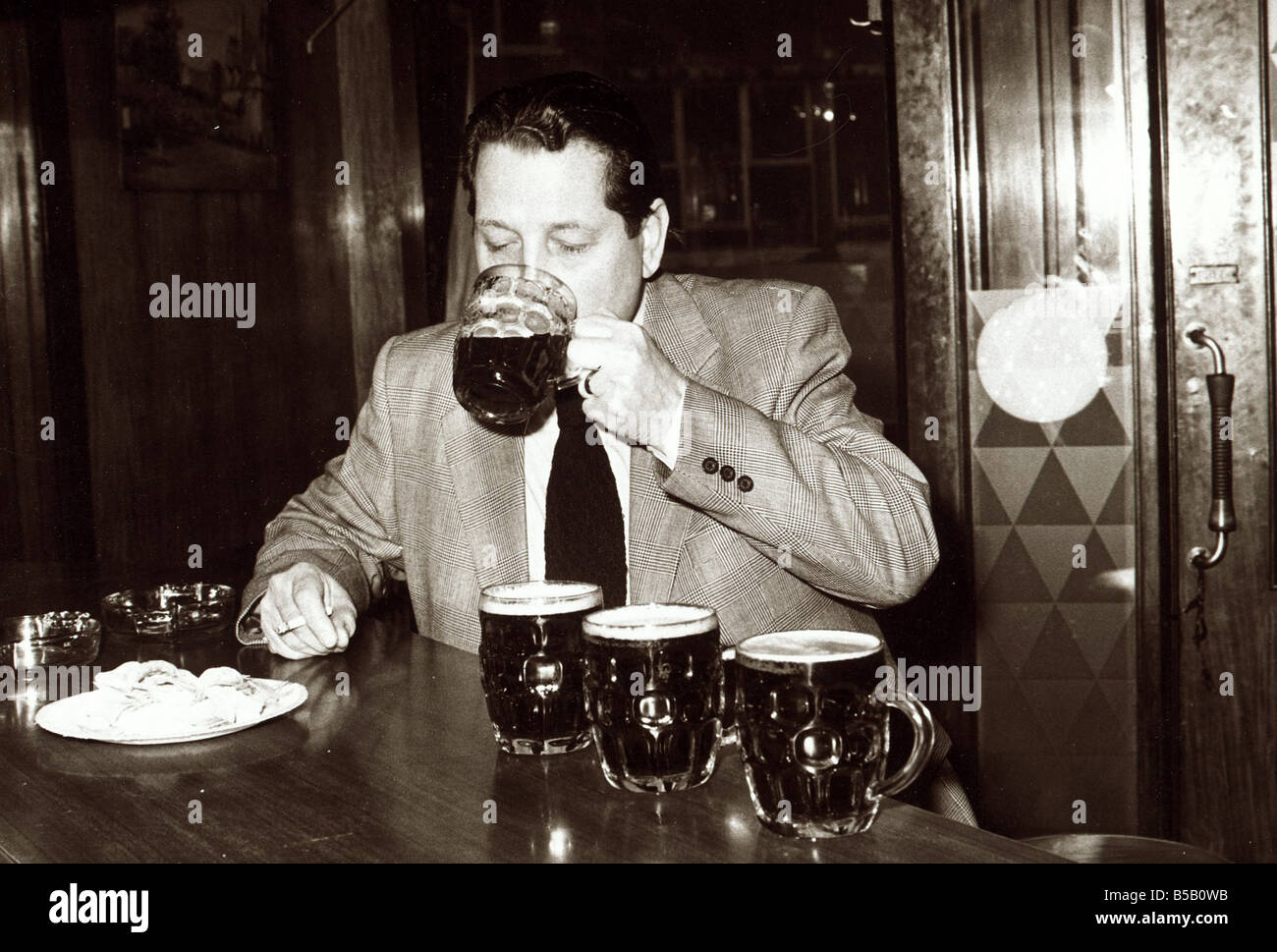 Man in pub drinking several pints of beer which are lined up on the bar ready February 1979 Stock Photo