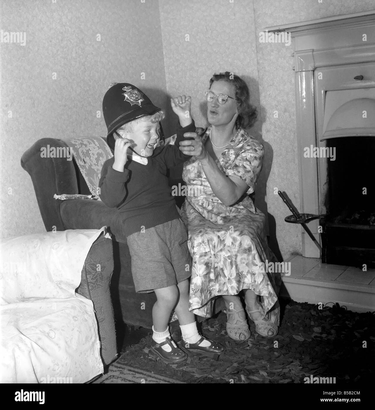 Child playing, pretending to be a policeman: Kenneth Knowles of Manchester seen here crying as his mother tries to remove the policeman's helmet. September 1957 Stock Photo