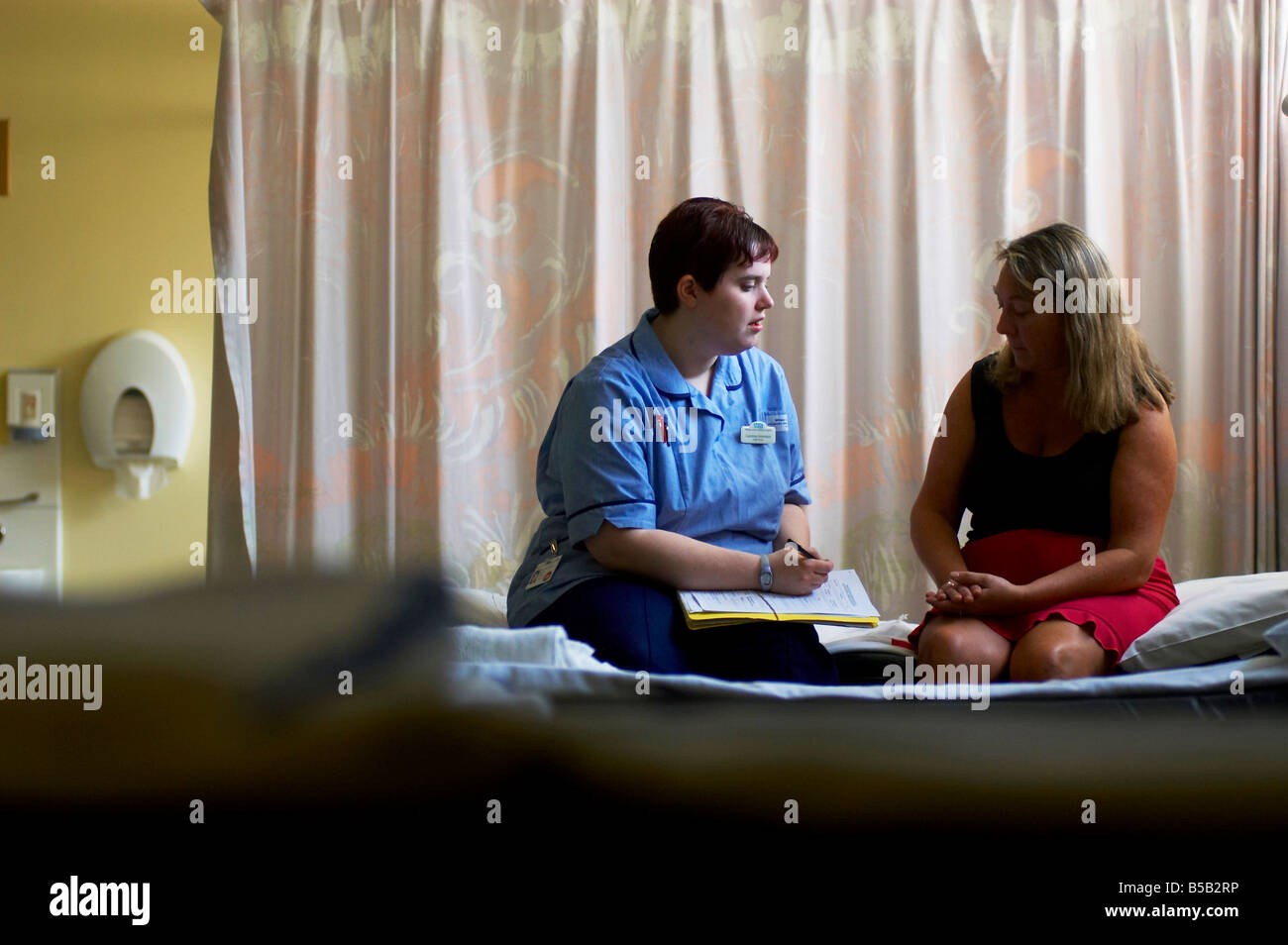 A staff nurse talks to patient on a ward Stock Photo - Alamy