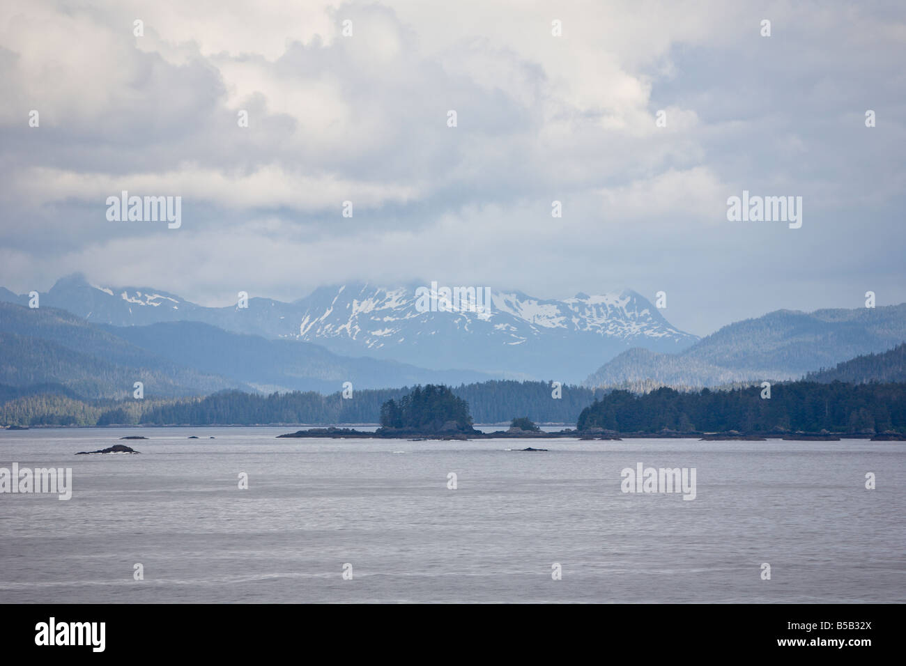 Snow capped mountains loom behind waters of the Inside Passage near Sitka, Alaska Stock Photo