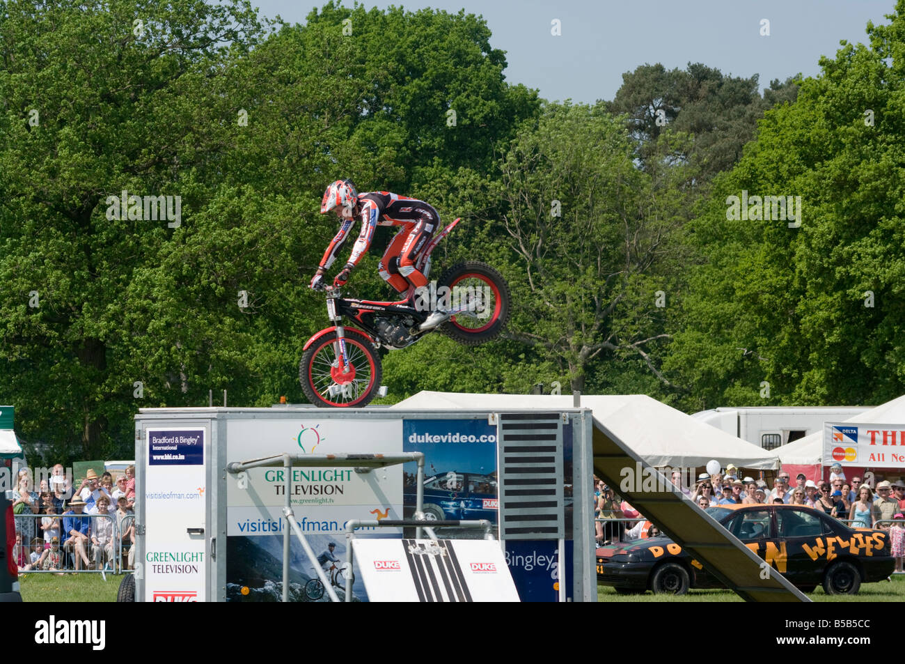 Motorcycle Stunt Rider riding his Motorcycle Stopping On His Front Wheel on the Roof of a Trailer doing stunts at village fete Betchworth Surrey uk Stock Photo