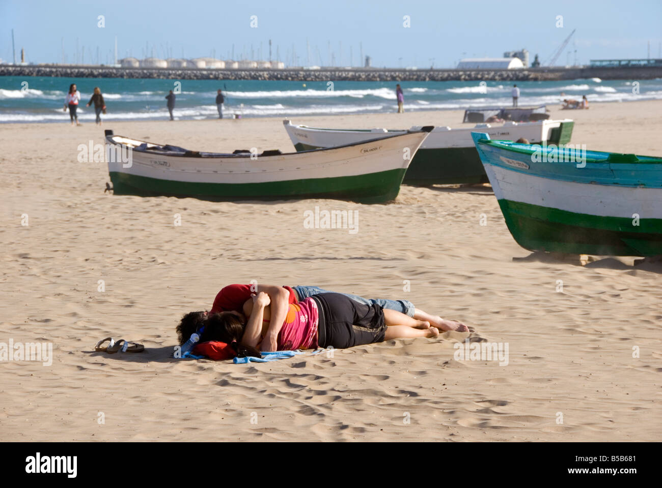 Couple sleeping on a beach with wooden boats on Playa Malvarrosa in the city of Valencia Spain Stock Photo