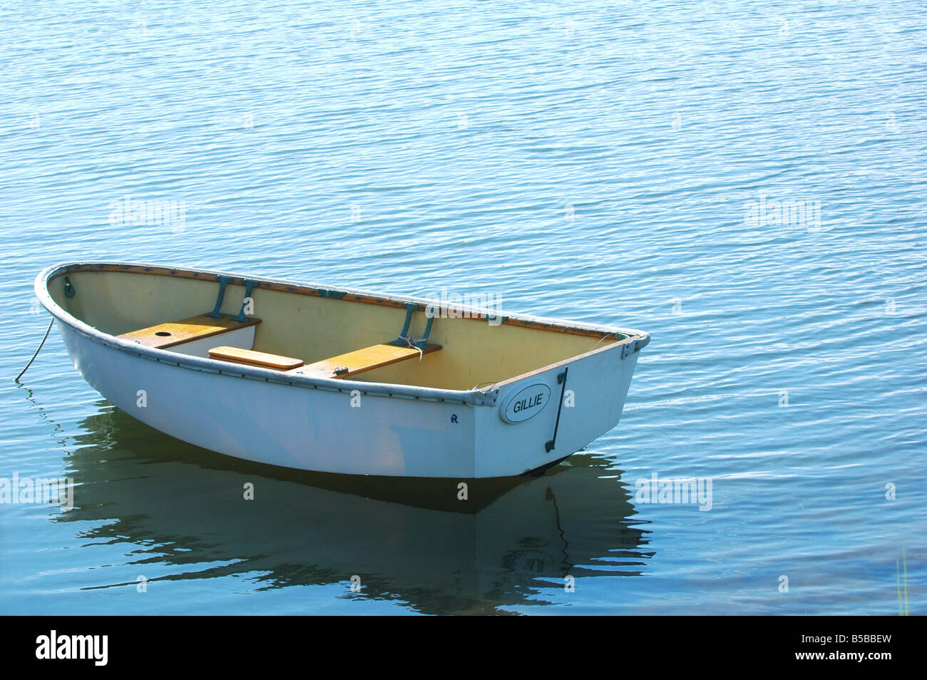 small empty row boat alone on a lake in the daylight in rippling waters Stock Photo