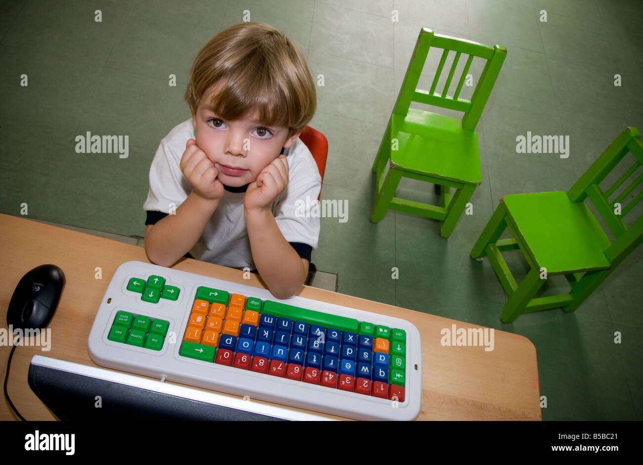 Computer & infant child blond boy in kindergarten primary school looks