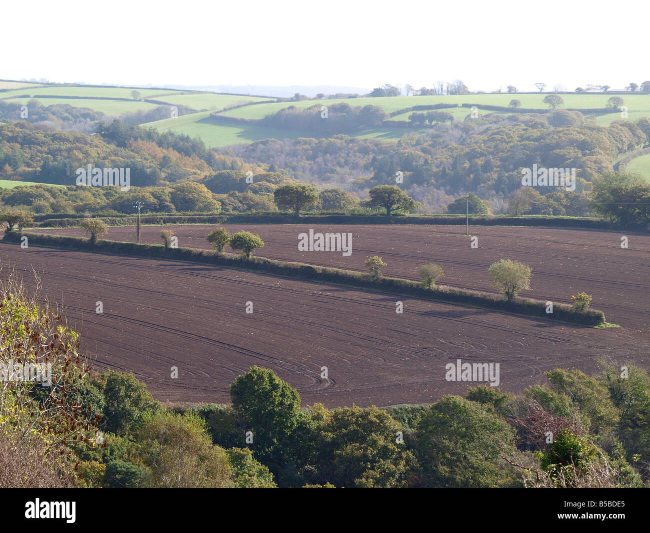 Farmed field in autumn, with countryside behind it Stock Photo - Alamy