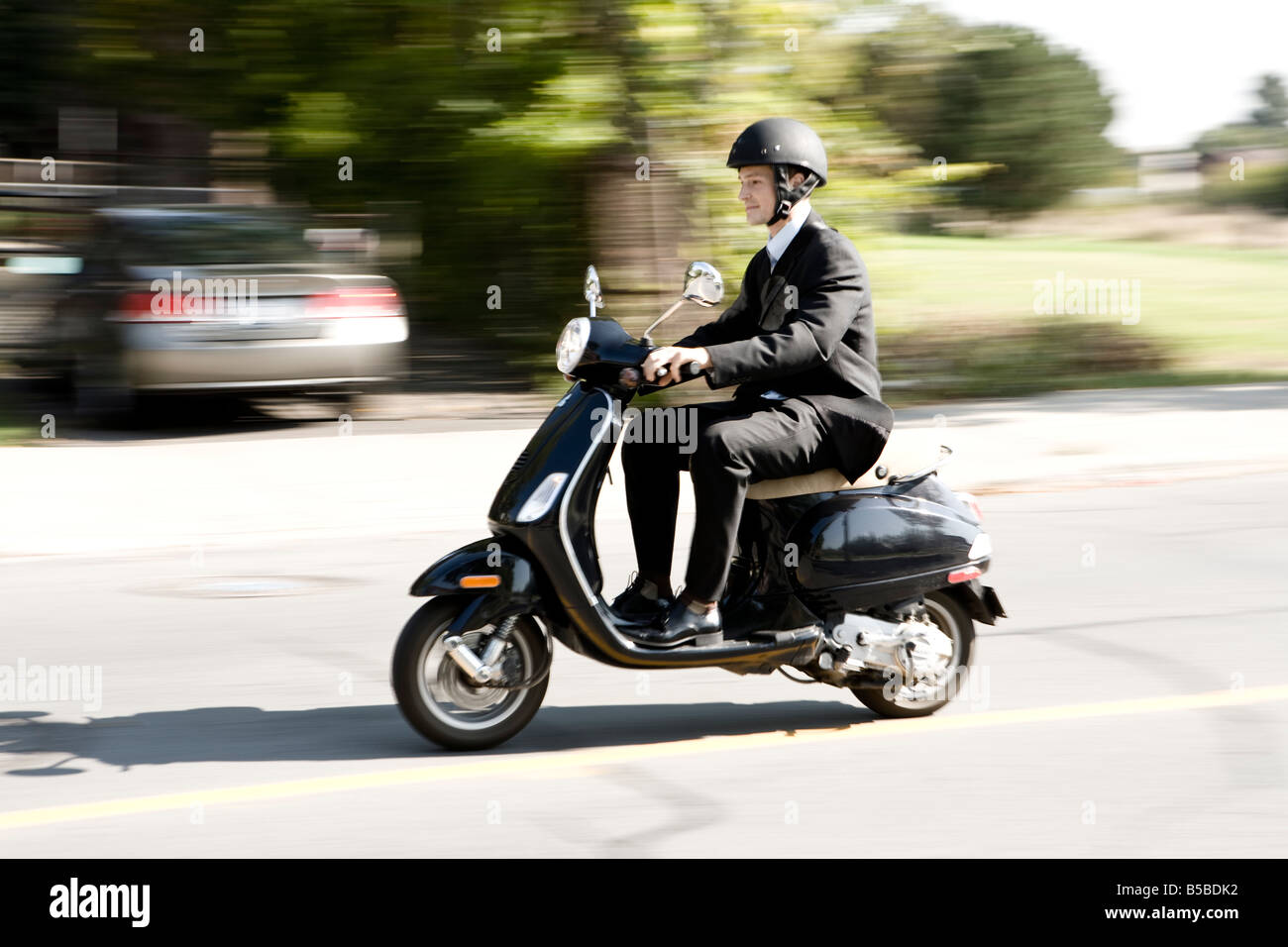 30 year old Caucasian male wearing a business suit riding a scooter