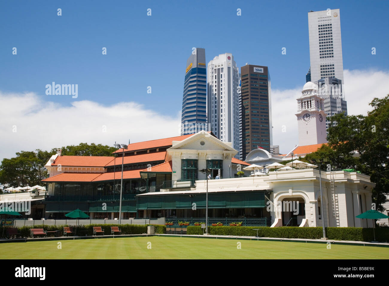 Padang Cricket Ground Clubhouse built in 1884 and modern skyscrapers of Raffles Place in downtown Central Business, Singapore Stock Photo