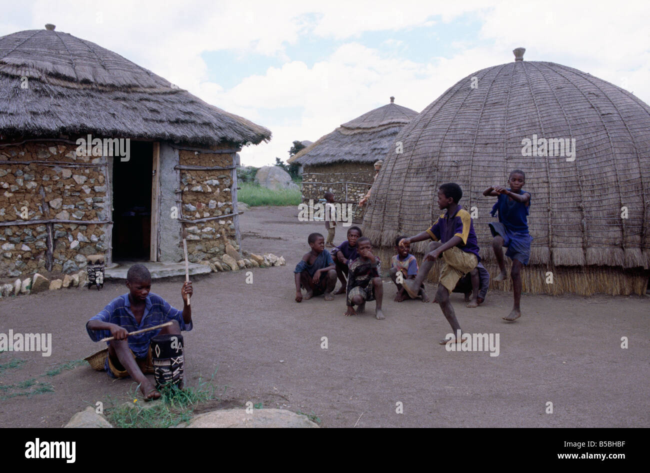 Traditional dome shaped huts Thatched bound straw Boys dancing Man with