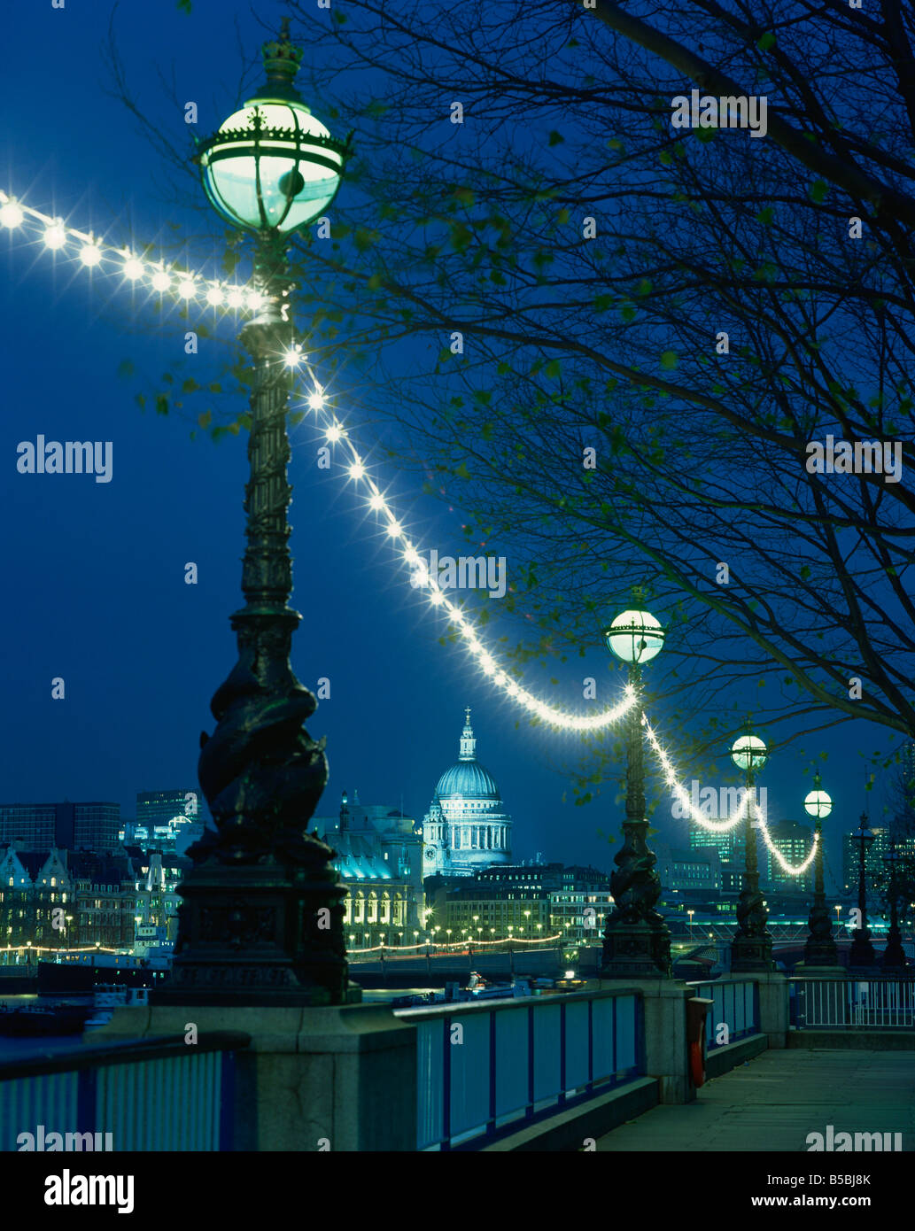 South Bank street lamps and city skyline including St Paul s Cathedral illuminated at night seen from across the Thames London Stock Photo