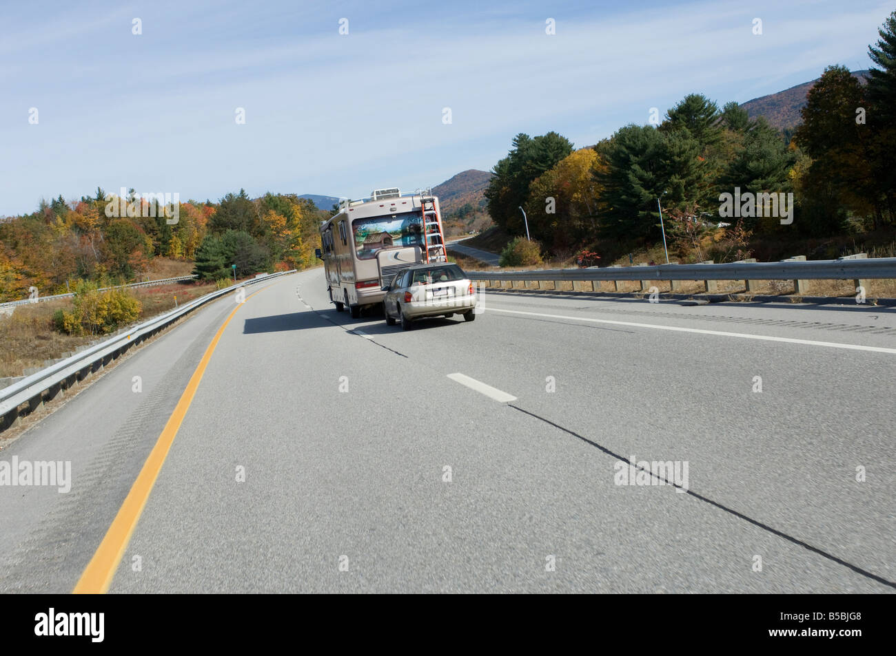 A mobile home towing a car driving on a two lane road in New Hampshire USA Stock Photo