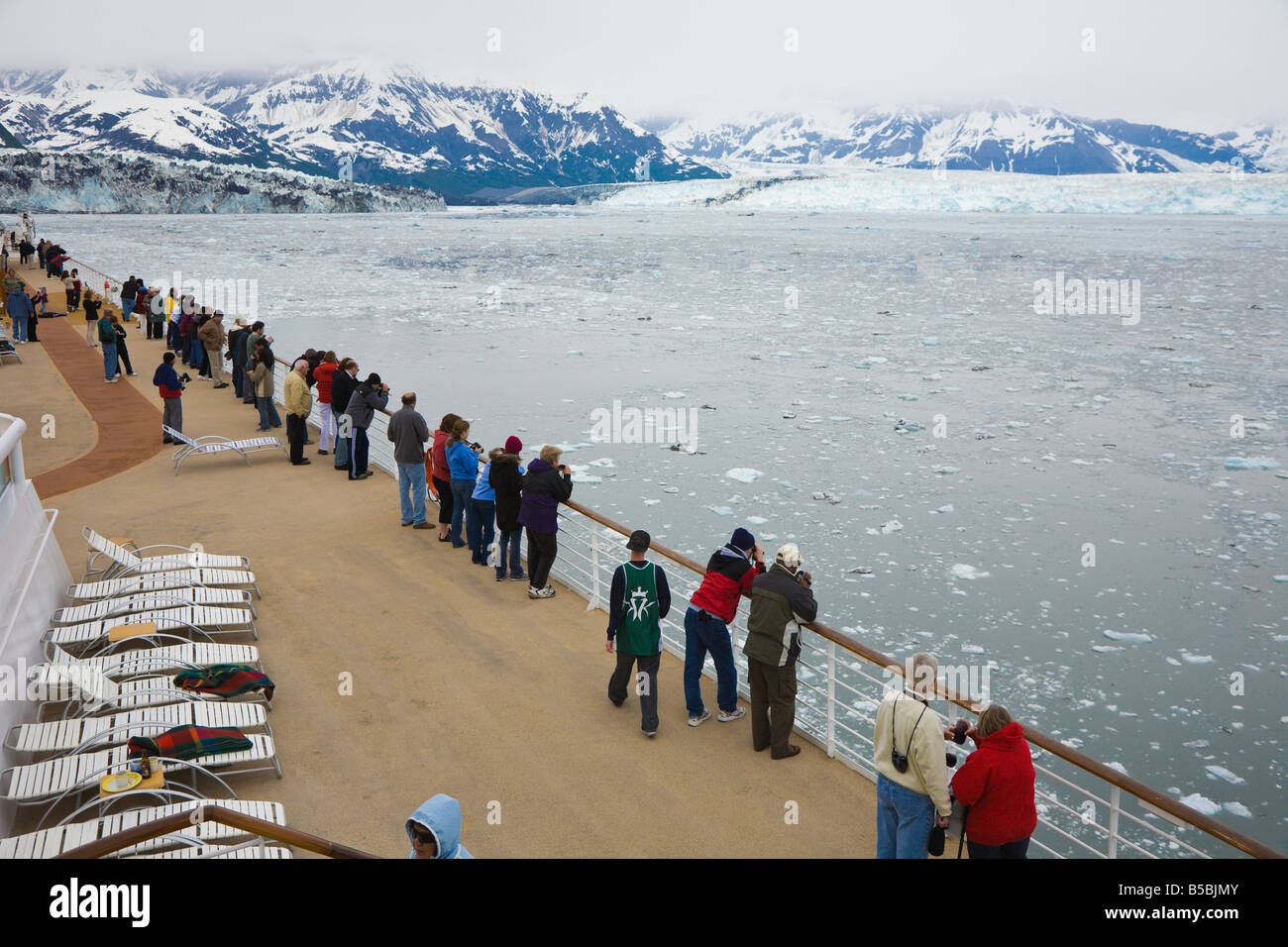 Cruise ship passengers line deck railing to see Hubbard Glacier in Disenchantment Bay and Yakutat Bay in Alaska Stock Photo