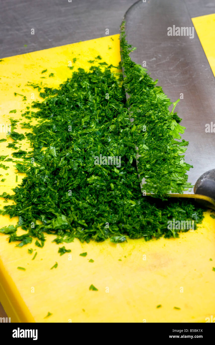 Cutting fresh Parsley in a yellow cutting board Stock Photo