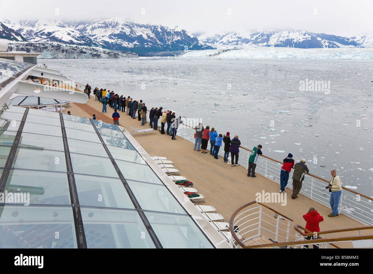 Cruise ship passengers line deck railing to see Hubbard Glacier in Disenchantment Bay and Yakutat Bay in Alaska Stock Photo